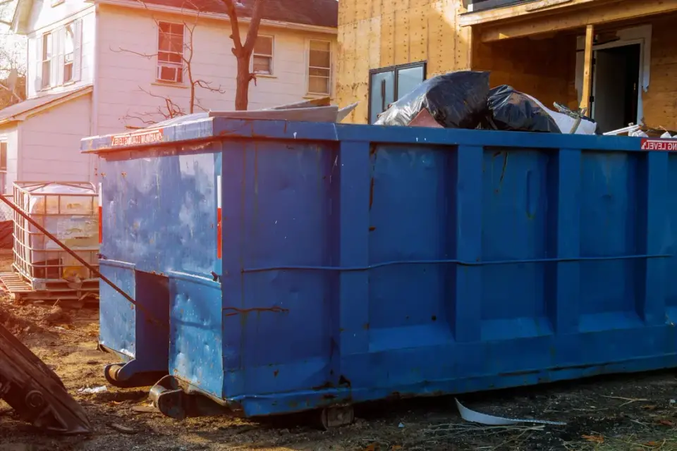 Roll-off dumpster filled with roofing shingles and tear-off debris