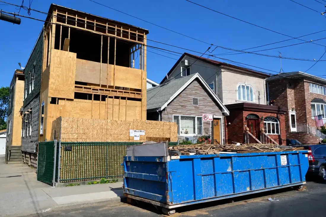 Roll-off dumpster full of debris outside a home under renovation